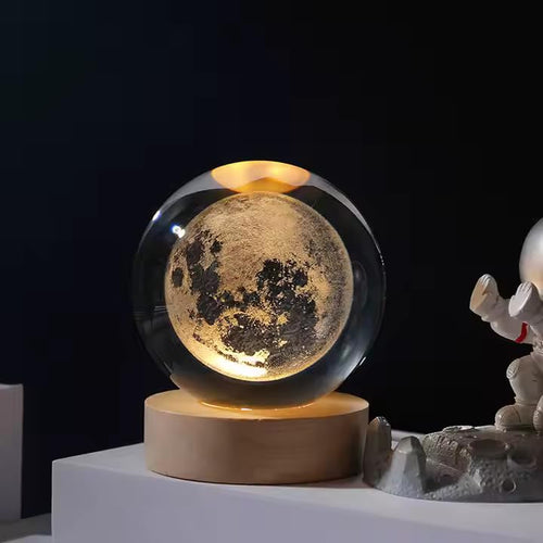 Moon-themed crystal ball on a wooden base with a dark background