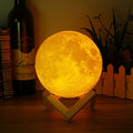 Moon lamp on a wooden stand with a bottle and books in the background