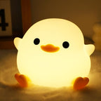 Cute chick-shaped night light glowing softly on a soft surface.