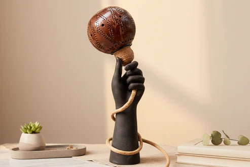 Decorative lamp with a hand holding a ball on a neutral background