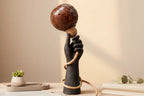 Decorative lamp with a hand holding a ball on a neutral background